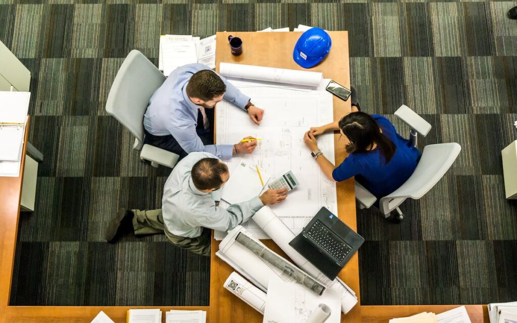 Three colleagues sit around a table having a planning meeting.